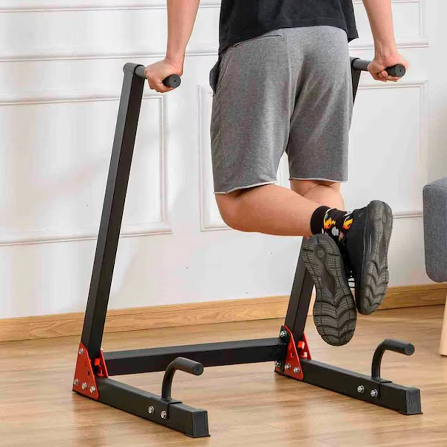 Person using a black exercise machine on a wooden floor.