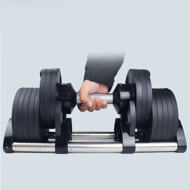 Hand holding a pair of adjustable dumbbells against a light gray background