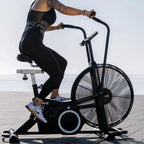 Person using an exercise bike outdoors with a clear sky background