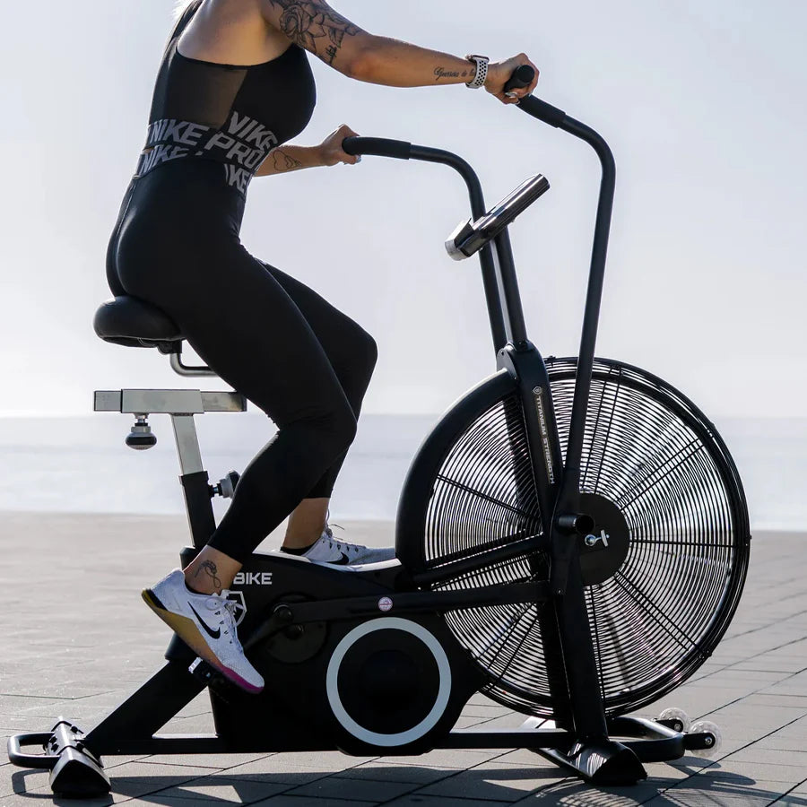 Person using an exercise bike outdoors with a clear sky background