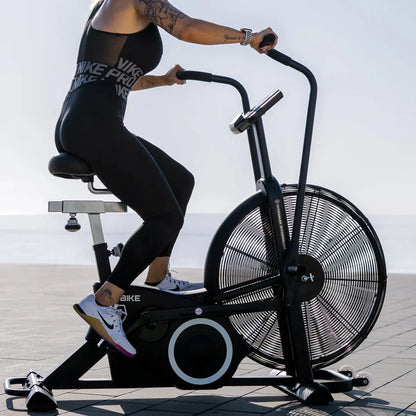 Person using an exercise bike outdoors with a clear sky background