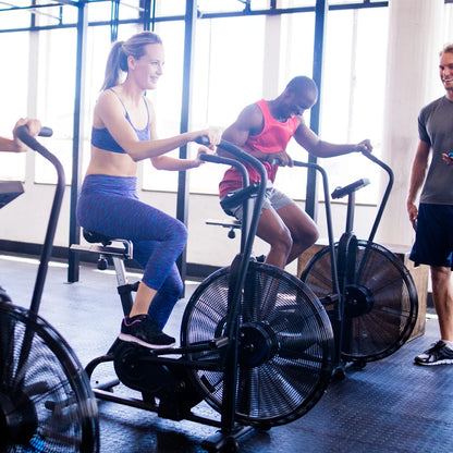 People exercising on air bike machines in a gym setting