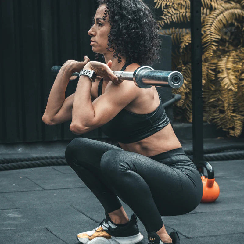 Woman performing a squat with a barbell in a gym setting
