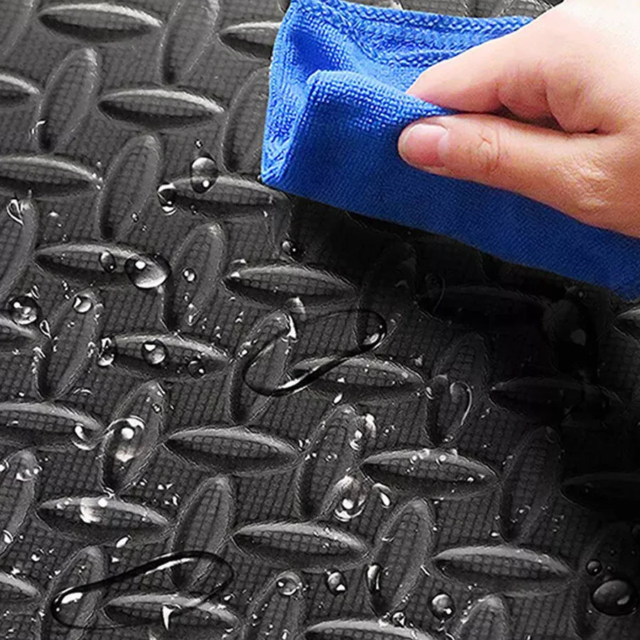 Person cleaning a textured black mat with a blue microfiber cloth.