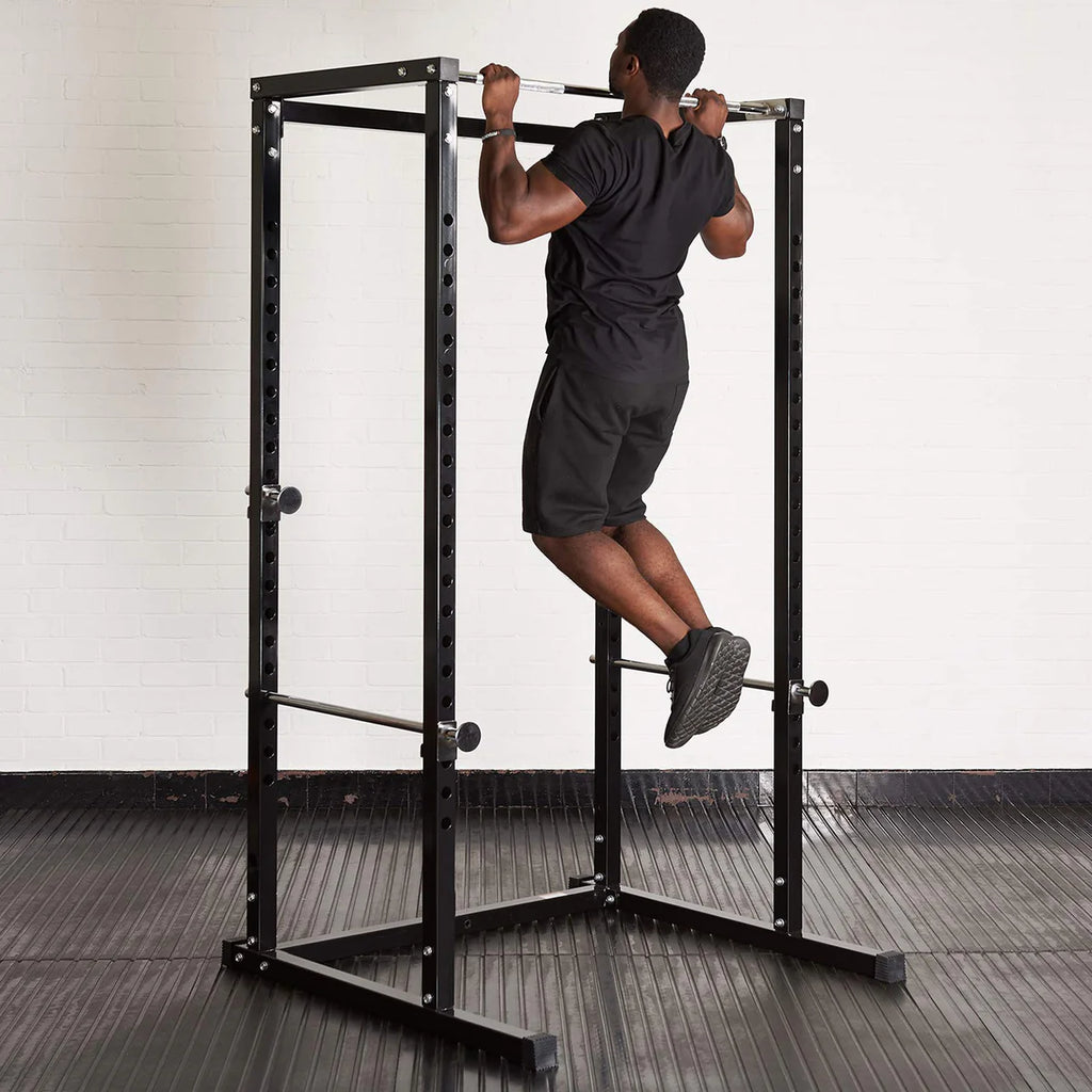 Person using a black power rack in a gym setting