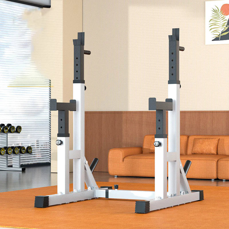 White and black squat rack in a home gym setting with an orange couch and window blinds.